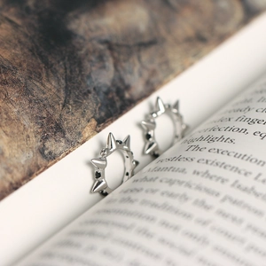 Close-up of 925 sterling silver spike hoop earrings placed on open book pages
