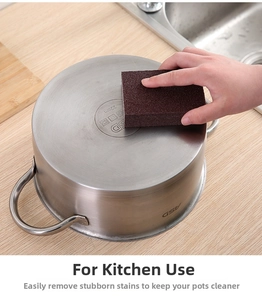 Close-up of hand using brown emery sponge to clean burnt stains on stainless steel pot bottom