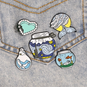 Set of creative enamel pins featuring starry night and whale designs on denim jacket