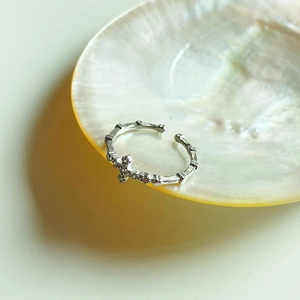 Detailed view of silver cross ring with cubic zirconia on a pearl shell background