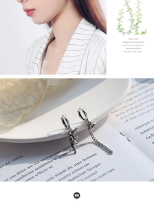 Detail view of asymmetric vintage silver earrings with fairy charm and long chain link