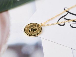 Macro detail of 18K gold coin pendant showing Elizabeth II engraving and refined texture