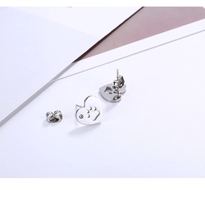 Détail de boucles d'oreilles cœur argentées avec motif patte et petite pierre précieuse