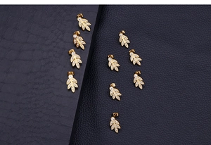 Detailed macro view of ten gold-toned leaf-shaped stud earrings with crystal inlays