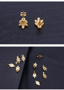 Detail view of gold leaf stud earrings with crystal rhinestones on black texture