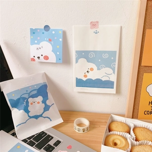 Close-up of cute cartoon bear sticky notes and mini paper bags on a wooden desk