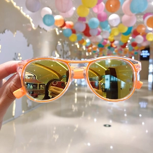 Detail of orange heart-shaped sunglasses with yellow lenses being held by hand