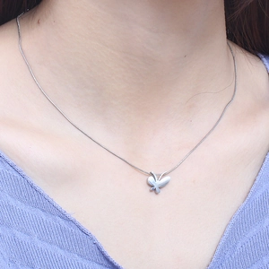 Minimalist silver butterfly necklace with snake chain worn on model in blue knitwear