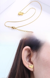 Detailed view of golden butterfly necklace and earrings set on white background