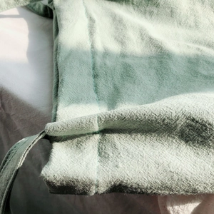 Detail shot of green washed cotton linen fabric with reinforced stitching and soft texture