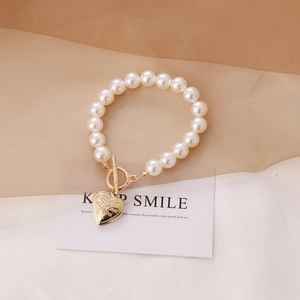 Detailed macro view of heart pendant with I Love You engraving on pearl bracelet