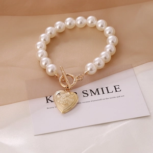 Detail of pearl necklace with gold OT buckle and heart pendant engraved with I Love You