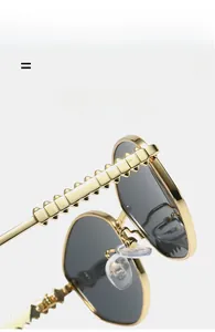 Detail of gold metal sunglasses frame featuring textured temples and grey lenses