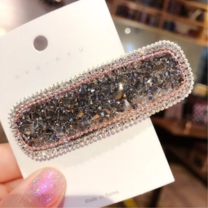 Dettaglio di un fermaglio rettangolare con strass grigio scuro e perline rosa