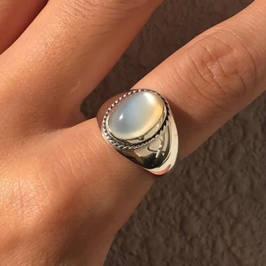 Close-up of 925 silver ring with oval white agate and rope-textured bezel on finger