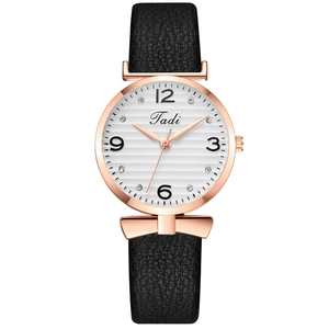 Détail du cadran rayé blanc avec strass et nœud en or rose sur une montre en cuir