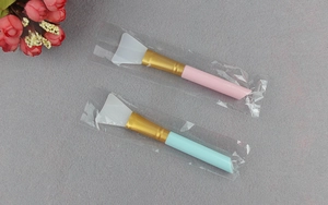 Detail of pink and blue silicone face mask brushes with soft white tips and gold tubes