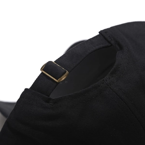 Detailed close-up of the adjustable strap and bronze metal buckle on a black baseball cap