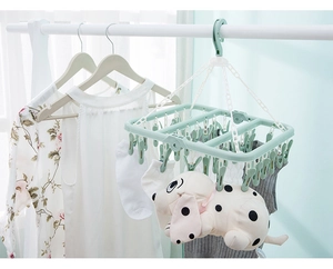 Detail of green folding laundry rack with 32 clips drying socks and plush toys