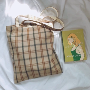 Detail view of a plaid canvas tote bag with brown and beige patterns on white cloth