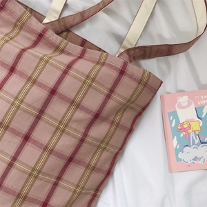 Flat lay of red checkered canvas tote bag with cream straps on white fabric background