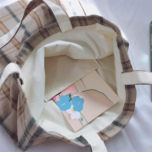 Macro view of plaid canvas tote bag interior showing the inner pocket and durable strap