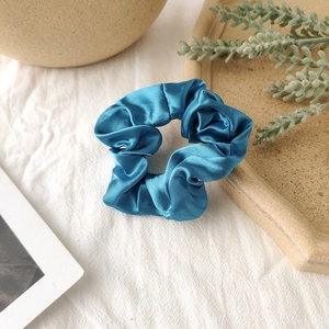 Detailed view of the soft pleated texture on a shiny blue satin silk scrunchie accessory