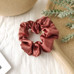 Detailed shot of smooth satin fabric texture on a caramel brown scrunchie hair tie