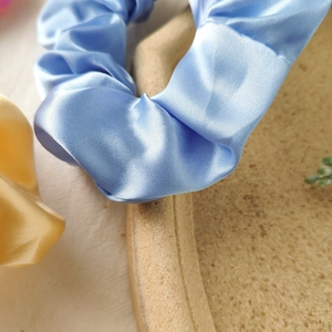 Macro shot of silk satin scrunchies with smooth texture and soft pastel color folds