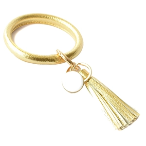 Detailed view of a gold faux leather wristband keychain with matching tassel and charm