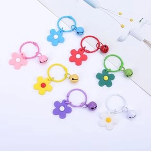 Macro detail of seven colorful flower charms with bells and metal key rings on white background