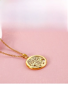Gros plan détaillé du pendentif rond Main de Hamsa avec incrustation en nacre et plaqué or