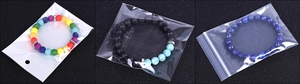 Three beaded bracelets with skulls in blue, black, and rainbow stone, individually bagged