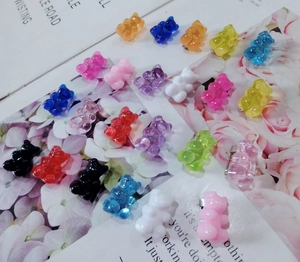 Detail shot of colorful resin gummy bear earrings with metal posts on floral paper