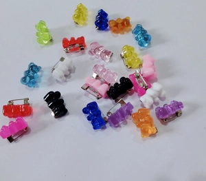 Close-up of colorful resin gummy bear pins scattered on a white background for backpacks