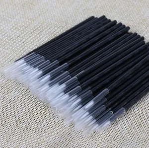 Detail view of white tipped micro applicators with black handles and clear caps on burlap