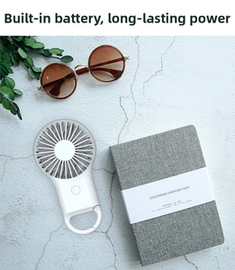 White portable mini fan with integrated bottom hook on a textured desk with sunglasses