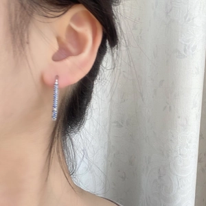 Close-up of long linear earrings with blue gems worn by a model in a natural setting