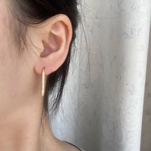 Detailed view of micro-pave gold safety pin earrings worn by a model in soft light