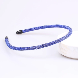 Close-up of a sparkling navy blue rhinestone headband with fine sequins on a white tray