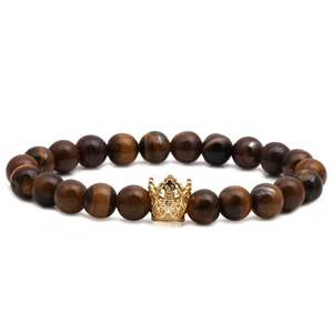 Tiger eye stone beaded bracelet with golden crown pendant on a white background