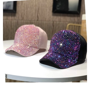 Dettaglio ravvicinato delle decorazioni in strass sulle berrette da baseball rosa e nere