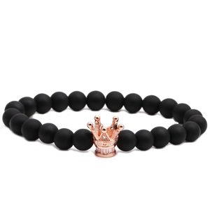 Bracelet en perles noires mates avec une couronne en or rose sur fond blanc pur
