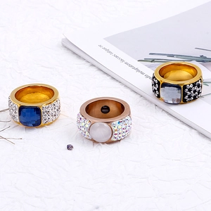 Exaggerated wide-face rings with colorful gemstones and pavé crystals on textured paper