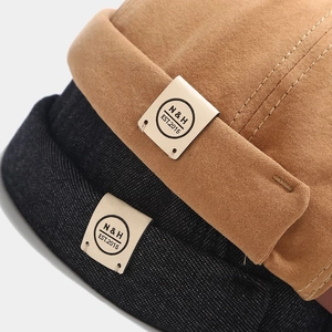 Gros plan de chapeaux Miki en toile empilés, kaki et noir, avec patch en cuir rétro