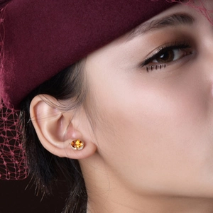 Close-up of elegant yellow gemstone stud earrings with micro diamonds on a model
