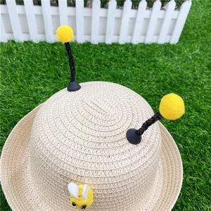 Close-up of woven straw texture with cute bee antenna decorations on a sun hat