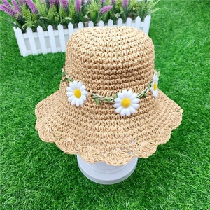 Handwoven beige straw sun hat for children featuring white daisies and wavy brim style