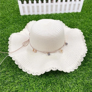 White straw beach hat with wavy brim and shell bead charms for summer sun protection