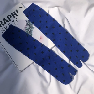 Detailed view of blue tabi socks with black number patterns and ribbed cuffs on a white cloth